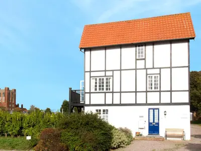a white house with a red roof and a blue door at 1 Bell Lodge, Thorpeness in Thorpeness