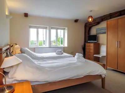 a bedroom with a large bed with white sheets at Meadow View, Near Aldeburgh in Aldringham