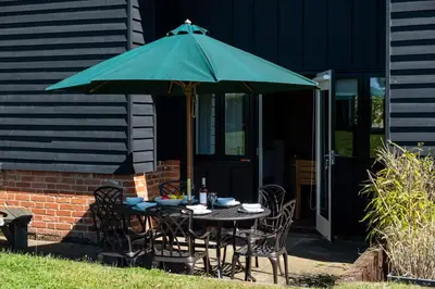 a table and chairs under a green umbrella at Meadow View, Near Aldeburgh in Aldringham