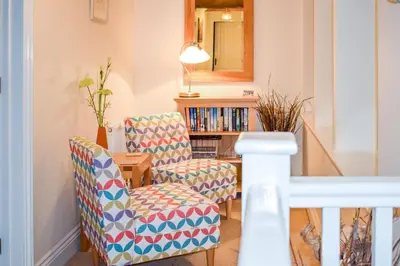 a living room with two chairs and a book shelf at Meadow View, Near Aldeburgh in Aldringham