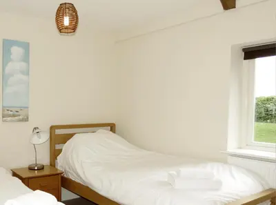 a bedroom with a bed with white sheets and a window at Meadow View, Near Aldeburgh in Aldringham