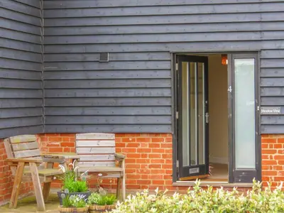 a house with a wooden door and a wooden bench at Meadow View, Near Aldeburgh in Aldringham