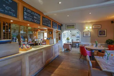 a restaurant with a bar and tables and chairs at Bedingfeld Arms in Swaffham
