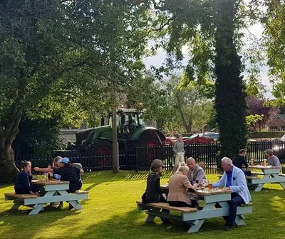 a group of people sitting at picnic tables in a park at Bedingfeld Arms in Swaffham