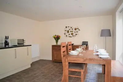 a dining room with a table and a kitchen at The Old Bottle Store - 2 Double Bedrooms, 2 Bathrooms, St Ives, Cambridgeshire in St Ives