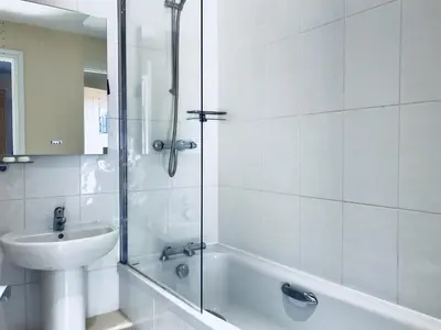a white bathroom with a sink and a shower at The Bird in Hand in Ashwellthorpe