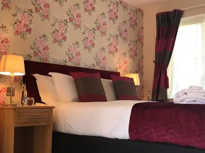 a bedroom with a large bed with pink floral wallpaper at The Bird in Hand in Ashwellthorpe