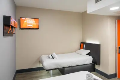 a room with two beds and a tv on the wall at easyHotel Ipswich in Ipswich