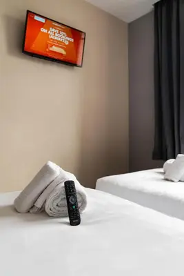a remote control sitting on a bed with a towel at easyHotel Ipswich in Ipswich