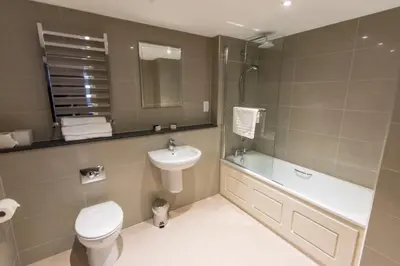 a bathroom with a sink and a toilet and a bath tub at St Nicholas Hotel Colchester in Colchester