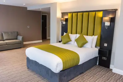 a bedroom with a large bed with a yellow headboard at St Nicholas Hotel Colchester in Colchester