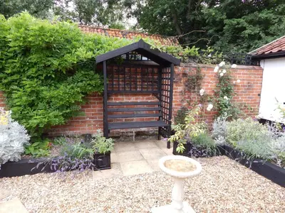 a garden with a bench in a brick wall at Frogs Hall B&B in Eye