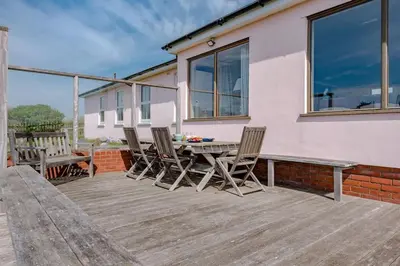 a wooden deck with a table and chairs on a house at Fairhaven, Thorpeness in Thorpeness