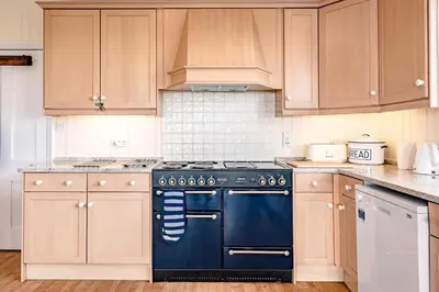 a kitchen with a black stove and wooden cabinets at Fairhaven, Thorpeness in Thorpeness