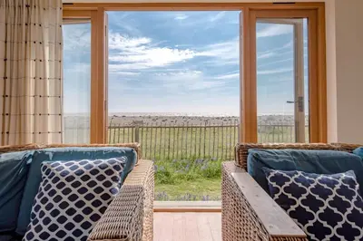 a room with two wicker chairs and a large window at Fairhaven, Thorpeness in Thorpeness