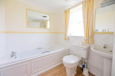 a bathroom with a tub and a toilet and a sink at Fairhaven, Thorpeness in Thorpeness