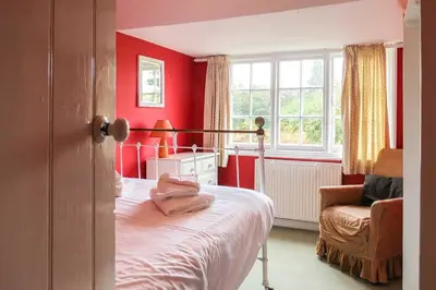 a bedroom with red walls and a bed and a chair at 7 Whinlands in Thorpeness