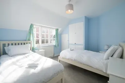 a bedroom with two beds and a blue wall at 7 Whinlands in Thorpeness