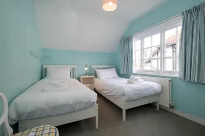 two beds in a room with blue walls and a window at 7 Whinlands in Thorpeness
