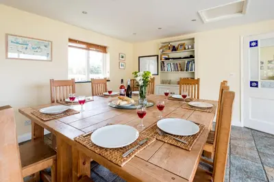 a dining room with a wooden table with glasses of wine at Crossing Cottage, Thorpeness in Thorpeness