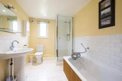 a bathroom with a tub and a sink and a toilet at Crossing Cottage, Thorpeness in Thorpeness