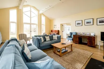 a living room with a blue couch and a table at Crossing Cottage, Thorpeness in Thorpeness