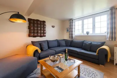 a living room with a blue couch and a table at 2 Ogilvie Lodge in Thorpeness