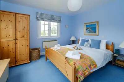 a bedroom with a large bed with blue walls at 2 Ogilvie Lodge in Thorpeness