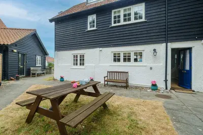 a wooden picnic table in front of a house at 2 Ogilvie Lodge in Thorpeness