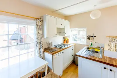 a kitchen with white cabinets and a window at 5 Coastguard Cottages in Aldeburgh