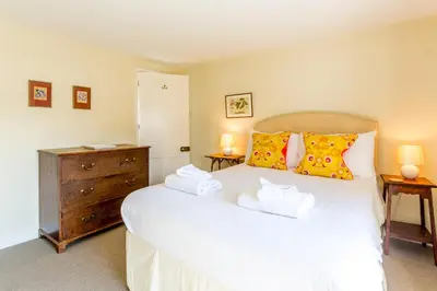 a bedroom with a large white bed with two towels at 5 Coastguard Cottages in Aldeburgh