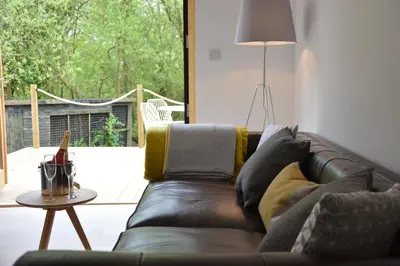 a brown leather couch in a living room with a table at Red Poll Barn in Spexhall