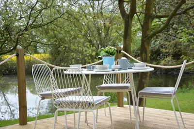 a table and chairs on a deck with a view of a pond at Red Poll Barn in Spexhall