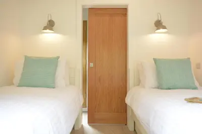 a room with two beds and a wooden door at Red Poll Barn in Spexhall