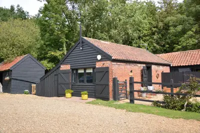 a black house with a brick building and a fence at Milk Parlour in Spexhall