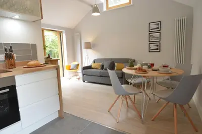 a kitchen and living room with a table and chairs at Milk Parlour in Spexhall
