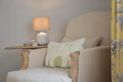 a chair with a pillow and a lamp on a table at Rookyards in Spexhall