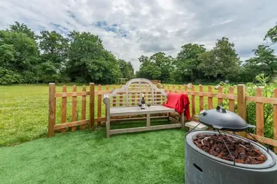 a wooden bench sitting next to a fence with a grill at Thompson Hall Retreat in Thompson