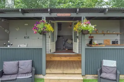 a patio with two chairs and two baskets of flowers at Thompson Hall Retreat in Thompson