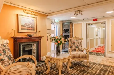 a living room with a fireplace and a table and chairs at Muthu Belstead Brook Hotel in Ipswich