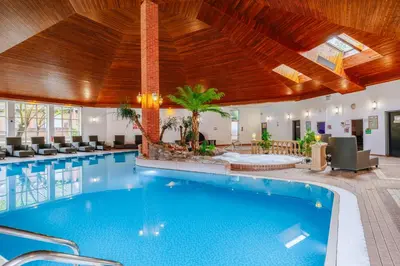 a swimming pool in a hotel with a wooden ceiling at Muthu Belstead Brook Hotel in Ipswich