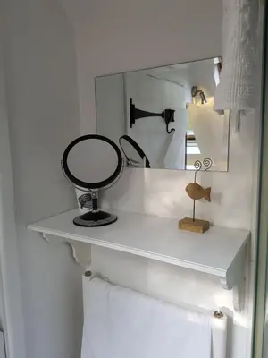 a white shelf with a mirror and towels at Wellrose Barn in Hertford