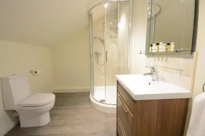 a bathroom with a shower and a toilet and a sink at King George Penthouse in Aldeburgh