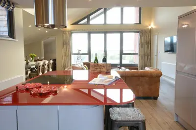 a kitchen and living room with a red counter top at King George Penthouse in Aldeburgh