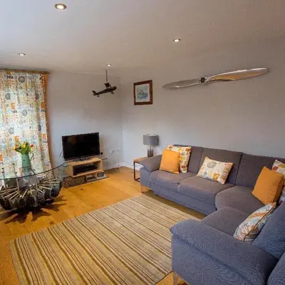 a living room with a blue couch and a tv at Fullers Hill Cottages in Little Grandsen
