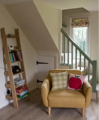 a living room with a chair and a book shelf at Fullers Hill Cottages in Little Grandsen