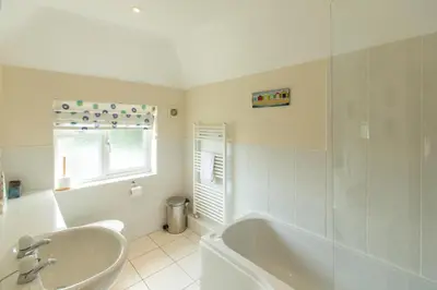 a white bathroom with a tub and a sink at 18 Pilgrim’s Way in Thorpeness