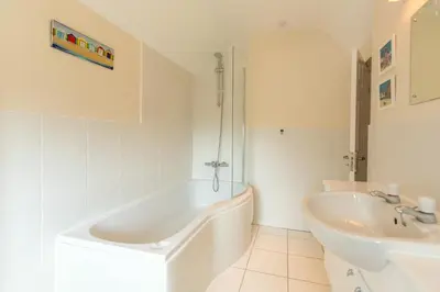 a white bathroom with a tub and a sink at 18 Pilgrim’s Way in Thorpeness