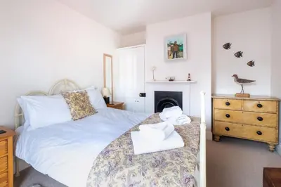 a bedroom with a white bed and a fireplace at The Old Gordon House - High Street location close to the beach and town amenities - Aldeburgh Coastal Cottages in Aldeburgh