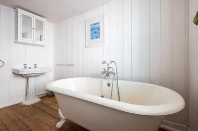 a white bath tub in a bathroom with a sink at The Old Gordon House - High Street location close to the beach and town amenities - Aldeburgh Coastal Cottages in Aldeburgh